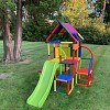 bild frontansicht farbenfroher kletterturm lina im garten plug-and-play baukasten lina mit rutsche und dach unter einem baum im garten
